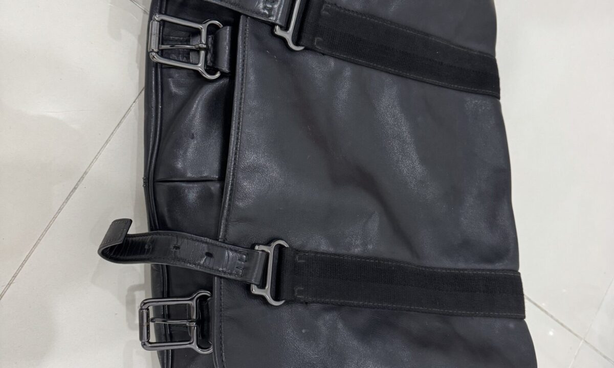 A well-travelled black leather carry-on bag