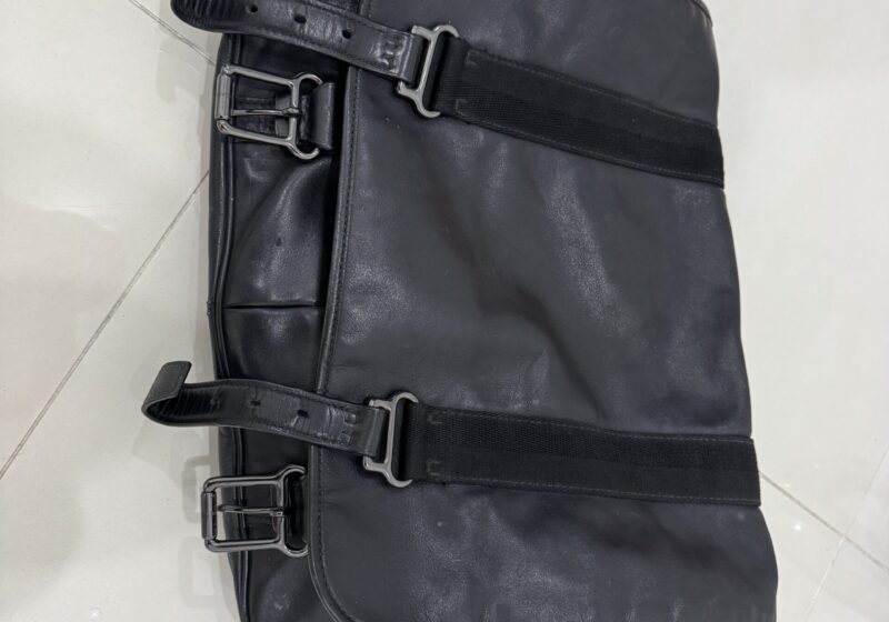 A well-travelled black leather carry-on bag