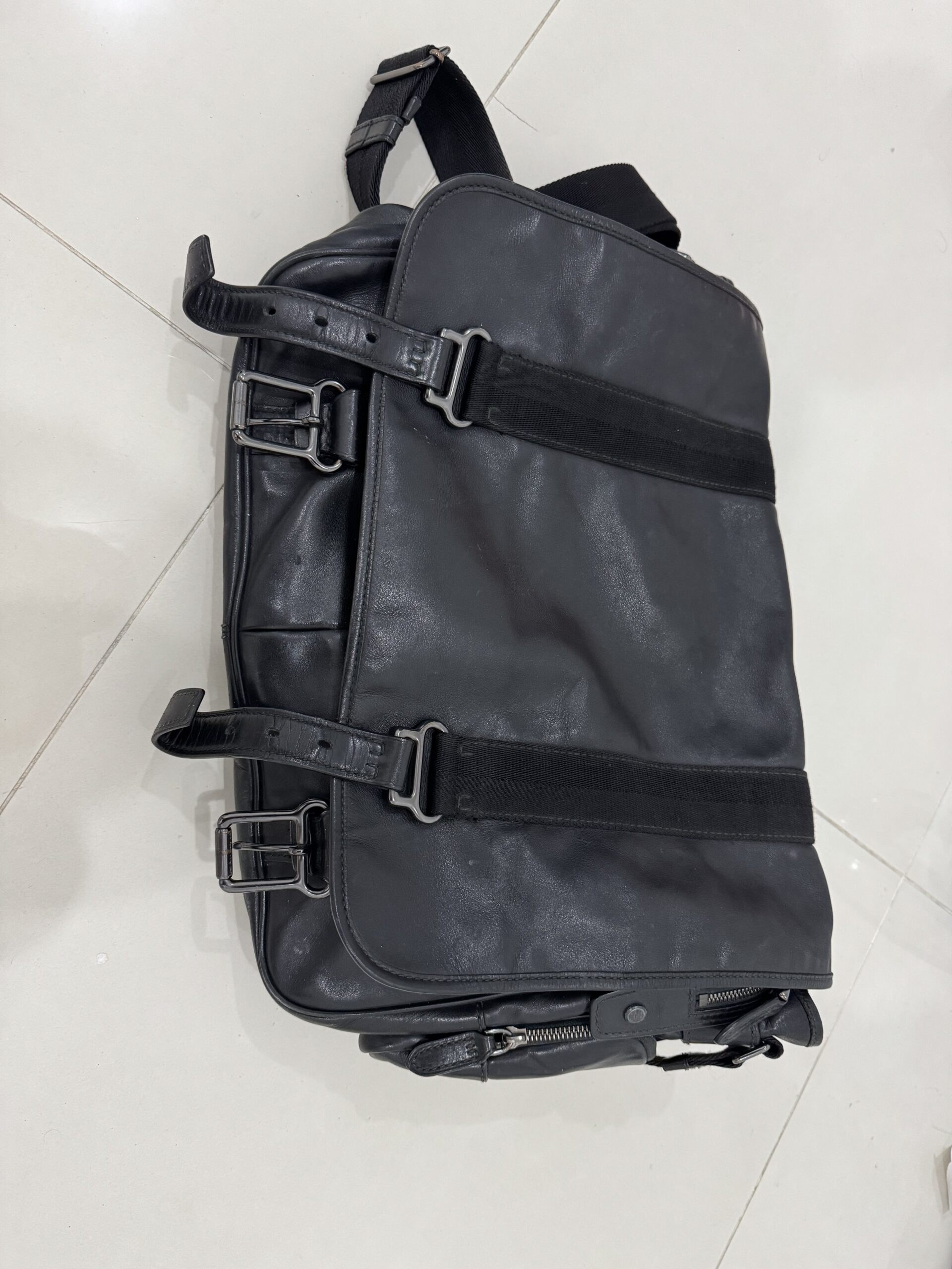 A well-travelled black leather carry-on bag